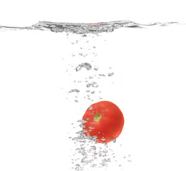 Fresh red tomato falling in water on white background