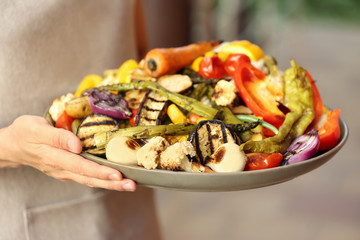 Woman holding plate with grilled vegetables