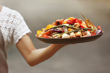 Woman holding plate with grilled vegetables