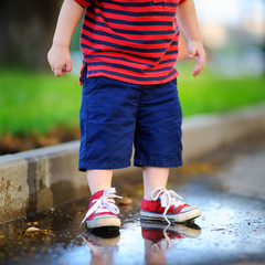 Toddler boy standing in a puddle