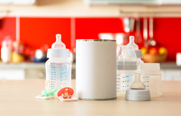 Feeding bottles with bank of baby milk formula on kitchen background