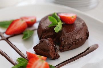 Chocolate fondant with strawberry on plate, closeup
