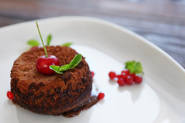Delicious fondant with cherry and red currant on plate, closeup