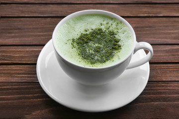 Cup of fresh matcha tea on wooden background