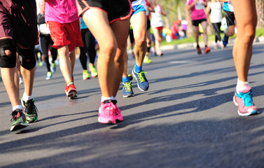Unidentified marathon athletes legs running on city road