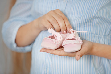 Pregnant woman with baby bootees at home