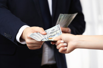 Man in suit taking bribe from woman hand closeup
