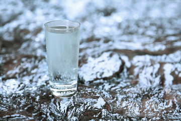 Glass of water on water background