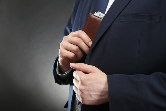 Businessman putting wallet with banknotes in suit pocket. Corruption concept