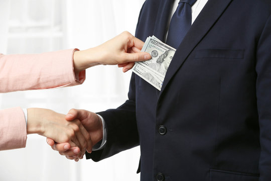 Man in suit taking bribe from woman hand closeup
