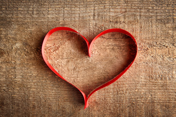 Red ribbon heart on wooden background