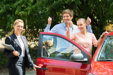 Couple Showing Key Of Newly Purchased Car