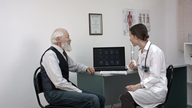 Doctor showing mri on laptop and telling good news to senior patient.