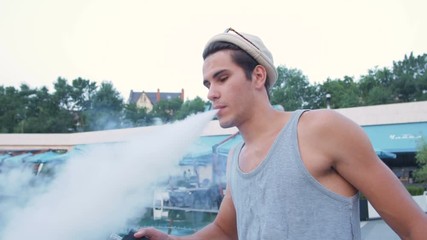 Young hipster man using an advanced personal vaporizer or e-cigarette