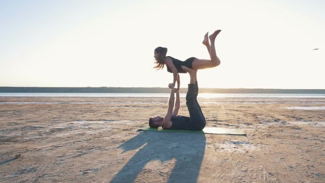 beautiful couple doing acro yoga on the beach, slow motion