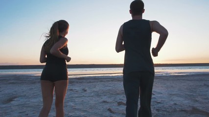 Young couple running on the beach at sunrise background, slow motion - Powered by Adobe