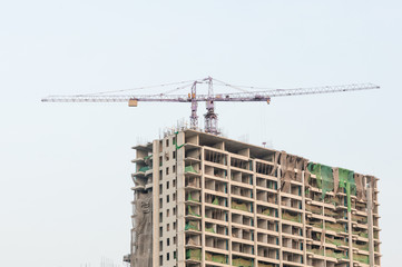 Fototapeta na wymiar Building site with high-rise block under construction in an urban environment dominated by a large industrial crane