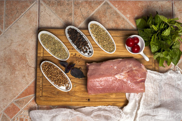 Fresh meat selection on wooden cutting board with spices in a white bowl