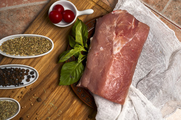 Fresh meat selection on wooden cutting board with spices in a white bowl