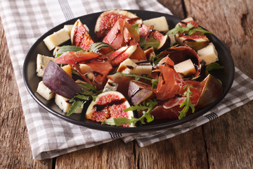Salad with figs, blue cheese, arugula and ham dressed with balsamic sauce close-up. horizontal
