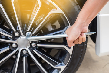 Hands disassembling a modern car wheel (steel rim) with a lug wr