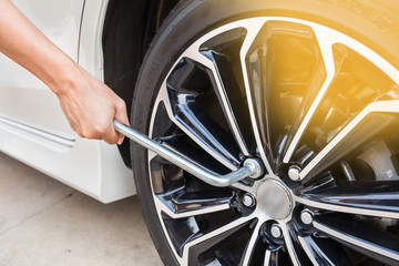 Hands disassembling a modern car wheel (steel rim) with a lug wr