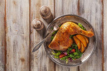 Baked chicken leg, served with roasted potatoes and vegetables.