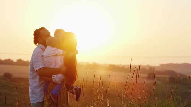 Big family hugging at sunset. Parents and two children