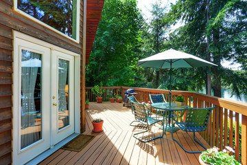 Balcony house exterior with patio area and opened green umbrella.