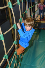 Kind hangelt im Seilnetz im Indoor-Freizeitpark