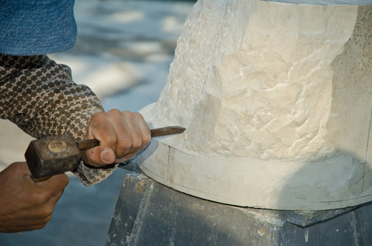 Man with hammer working on stone statue