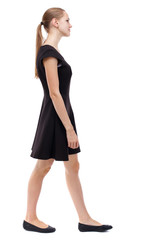 Fototapeta premium back view of walking woman. beautiful girl in motion. backside view of person. Rear view people collection. Isolated over white background. Blonde in a short black dress out of the frame.