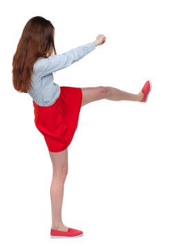 skinny woman funny fights waving his arms and legs. Isolated over white background. Long-haired brunette in red skirt is cancer and has foot.