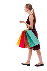 side view of going  woman  with shopping bags . beautiful girl in motion.  backside view of person.  Rear view people collection. Isolated over white background. Slim blonde in a burgundy dress