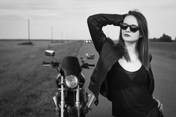 Plakat Biker girl in a leather jacket posing near motorcycle