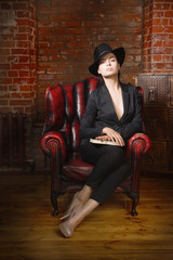 Elegant fashionable woman wearing black suit and hat in a vintag