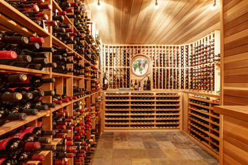 Bright home wine cellar with wooden storage units with bottles.