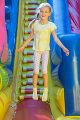 Fototapeta na wymiar Happy girl jumping on an inflatable trampoline