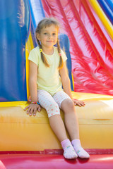 Fototapeta na wymiar Five-year girl sitting on a big inflatable trampoline