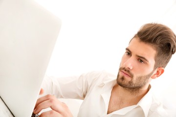 Fototapeta premium Attractive young man sitting at the table with a laptop computer..