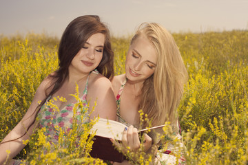 Naklejka na ściany i meble beautiful young smiling girls reading book against of yellow flo