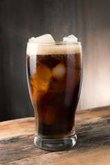 Cold fizzy cola soda with ice in glass cup