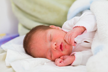 Little newborn child sleeping in her mother's arms some hours after her birth.