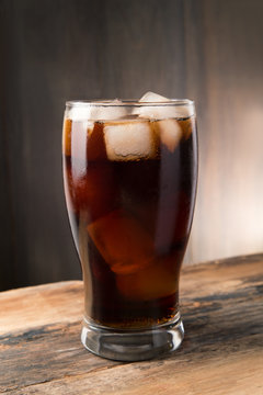 Cold fizzy cola soda with ice in glass cup