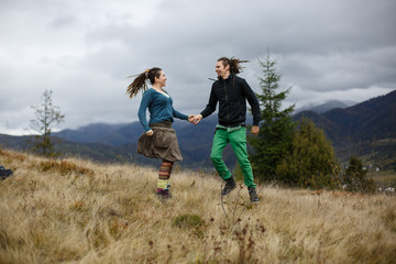 Couple with dreadlocks jumps on the mountain hill before great l