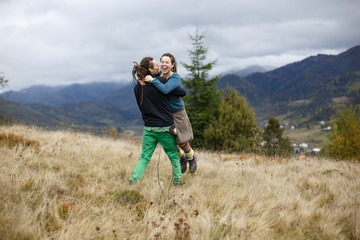 Woman smiles while man with dreadlocks whirls her on the hill wi © IVASHstudio