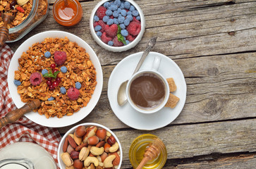 Breakfast table - berries, homemade granola, milk, dried fruits, nuts on wooden background. Copyspace background.Top view.