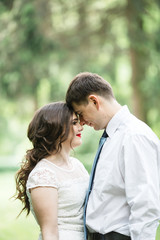 Fototapeta premium Bride and groom lean to each other foreheads while standing in t