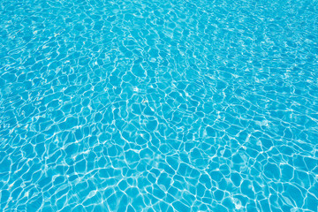 Fototapeta na wymiar Blue water surface with sun reflection in swimming pool
