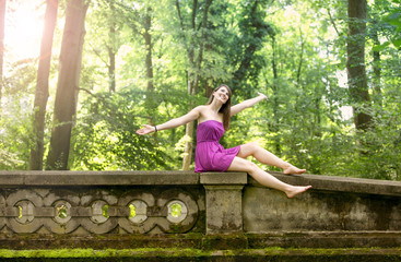 young woman sitting on bridge in park looking happy